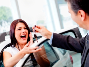 Salesman handling keys to a woman after buying a car